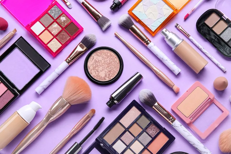 An array of makeup products on a purple background.